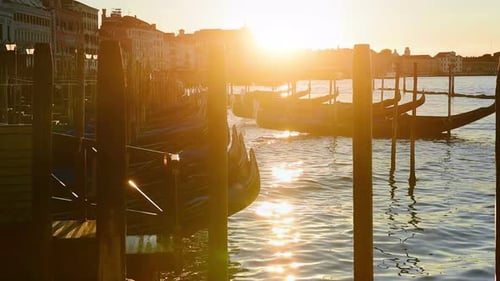 A beautiful shot of the sun setting behind rows of gondolas in Venice, Italy
