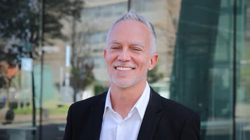 Close Up Portrait of Mature Adult Business Man with Gray Hair and Suit Smiling and Looking at Camera