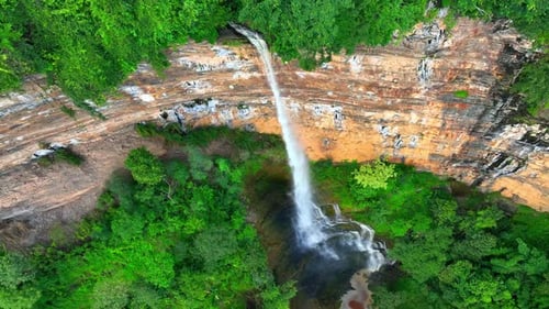 Drone captures majestic waterfall cascading from cliff.