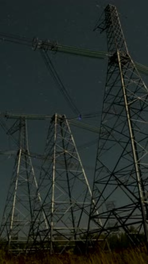 Electrical Towers Silhouetted at Night Under Starry Sky