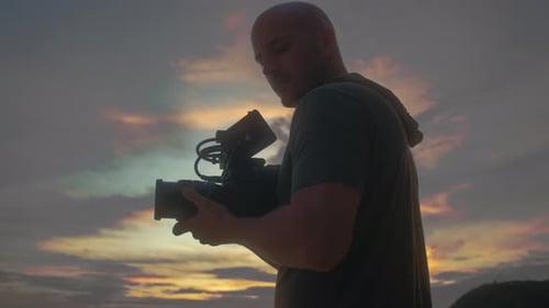 Man Holds Camera at Beautiful Sunset