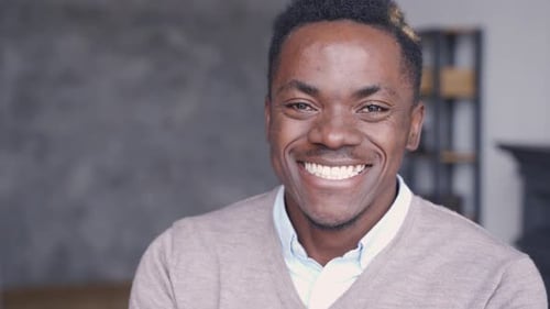 Smiling Cheerful Young Adult African Man Looking At Camera Standing At Home Office Background. Ha...