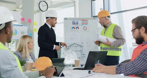 Homem, gerente principal de uma empresa de construção, realizando uma reunião com uma equipe profissional de especialistas em construção