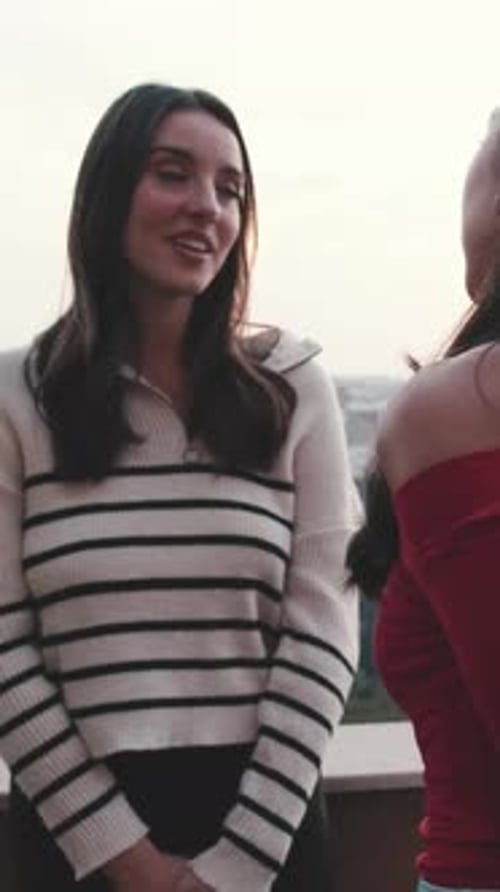 Two girls, friends chat while standing on the balcony on the modern city on the background