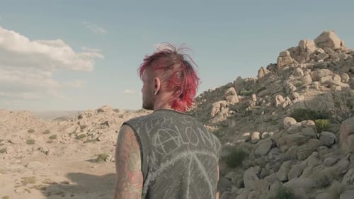 Punk male looks around, searching for something in a desert barren landscape.