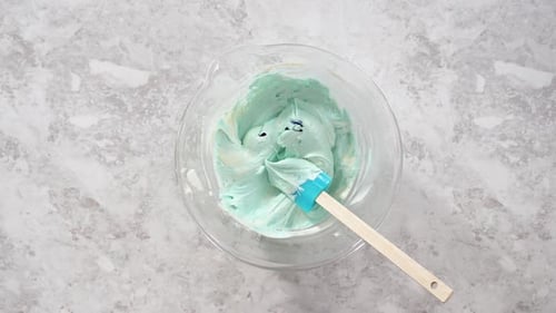 Flat Lay Mixing in Blue Food Coloring Into the Buttercream Frosting