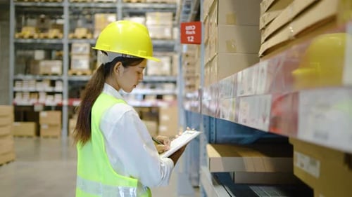 Lagerarbeiterin führt Bestandsaufnahme des Produktmanagements in Pappkartons in Regalen durch