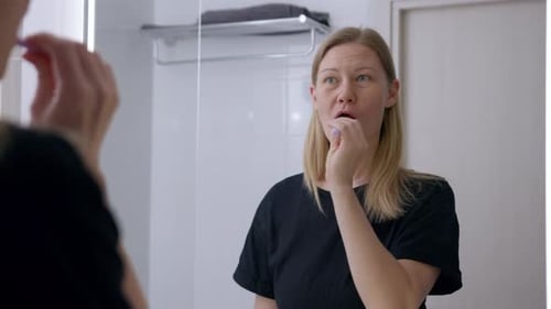Woman Brushing Teeth in Bright Bathroom