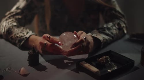 Woman's Hands Holding a Crystal Ball on Table