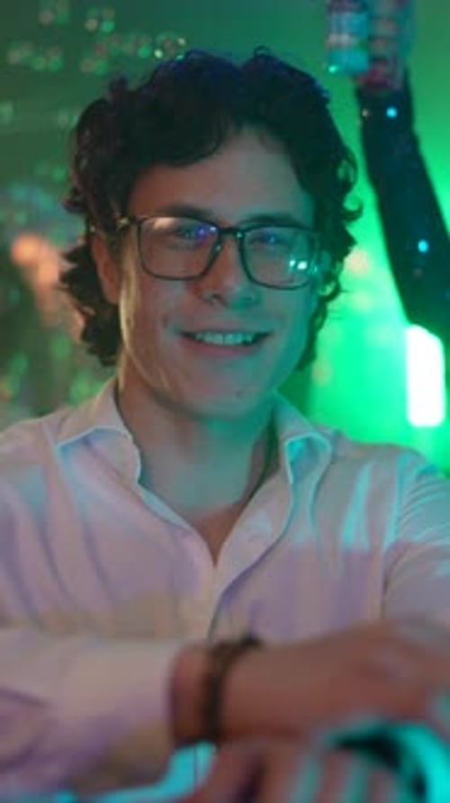 Young man dancing at a party with soap bubbles and colorful lights