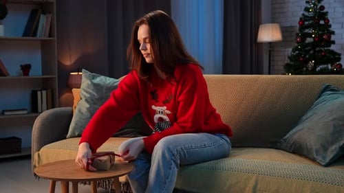 Woman Tying Bow on Christmas Gift at Home