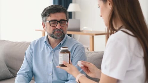 Showing pills. Mature man is visiting female doctor in the clinic