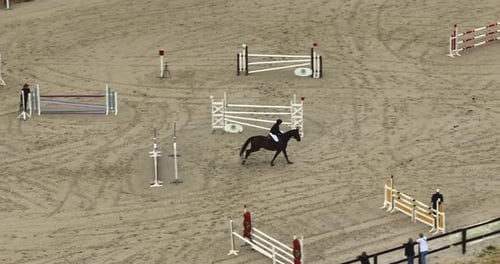 Wettbewerbe von Pferden und Reitern, die auf einem Pferderücken springen und einen Zaun auf Sandy Parkour springen