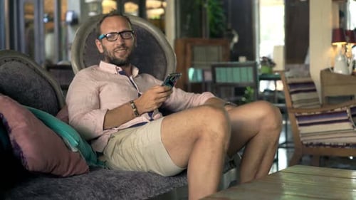 Portrait of Happy Man Talking to Camera Sitting in Trendy Cafe 30s