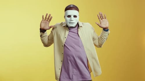 Masked Young Adult Dancing Against a Yellow Background