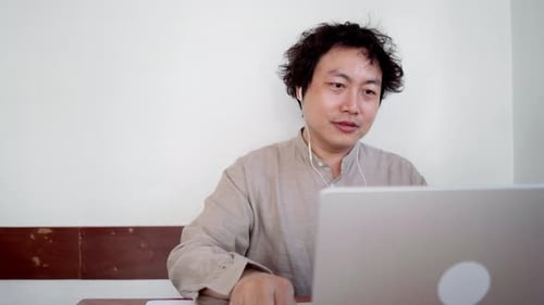 Adult man sit and take note for online meeting with laptop in cafe during daytime