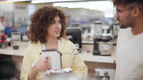Couple choosing hand mixer in electronics store in slow motion