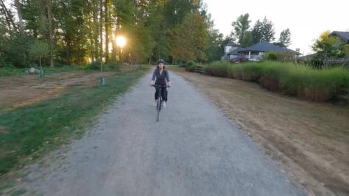 Adventure Woman Bike Riding on a Bicycle Trail Surrounded By Green Trees