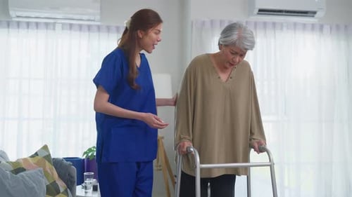 Woman assisting senior with walker in living room