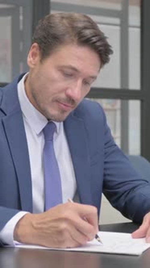 Man in Suit Writing on Paper at Desk