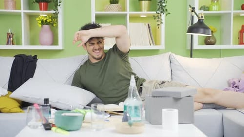 Young Adult Stretches and Grooms on Messy Couch