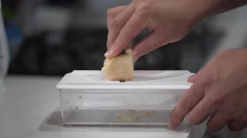 A man slicing fresh ginger with a slicer