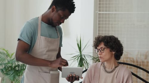 African American Waiter Offering Woman Dishes from Menu in Tablet