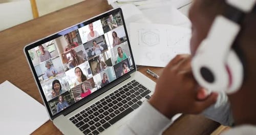 African american male college student holding notes and having a video conference on laptop at home