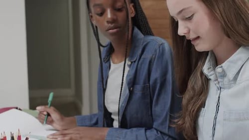 Des amies adolescentes concentrées et diversifiées qui étudient et discutent à table