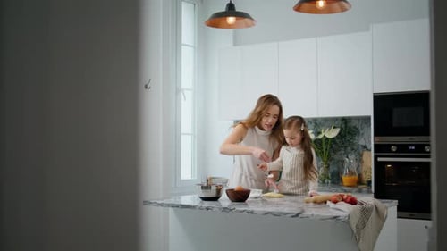 Woman and girl baking in a bright modern kitchen