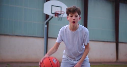 Video of a Boy Standing on a Basketball Court and Holding a Basketball Cinematic Shot of Teenager