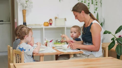 Woman and Children Eating Together at Table