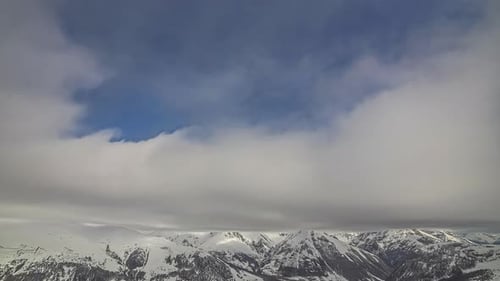 Cloudscape time lapse over scenic mountain range snow covered peaks - puffy white clouds flying thro