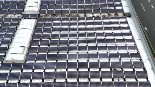 Solar panels on roof of warehouse during snowy winter day in USA. Low angle drone flyover. Productio