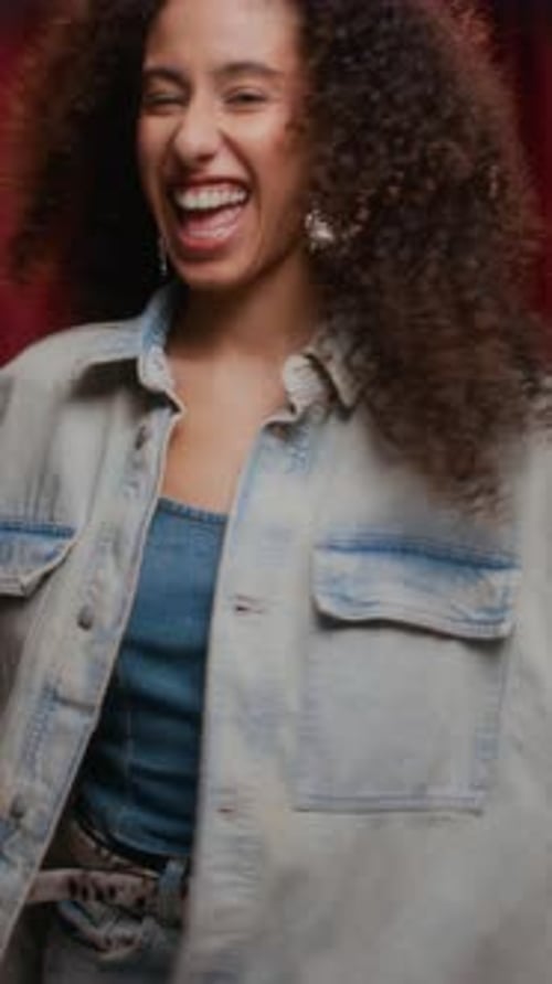 Young Biracial Woman in Denim Jacket Primping in Photo Booth