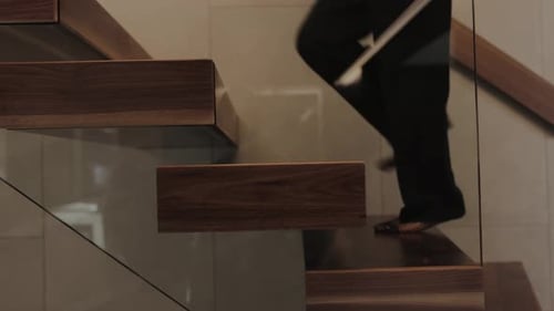 An Elegant Woman Walking Gracefully Up a Set of Modern Wooden Stairs in a Contemporary Setting