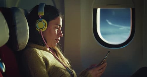 Cinematic shot of young woman with headphones listens favorite music with smartphone by using wirele