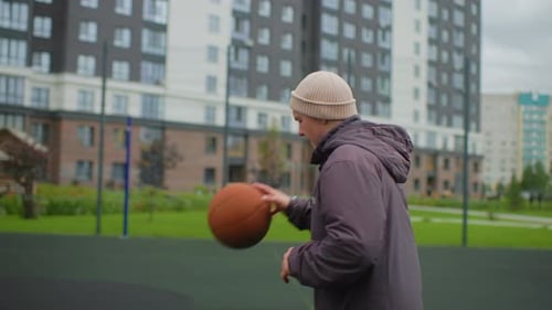 Young Man Dribbling Basketball on Outdoor Urban Court