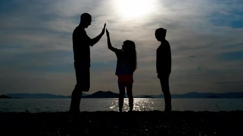 Silhouetted Family High Fiving on the Beach