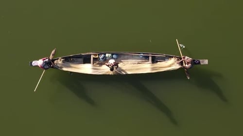 Aerial rising shot above 3 fishermen preparing their net to cast on a wooden boat