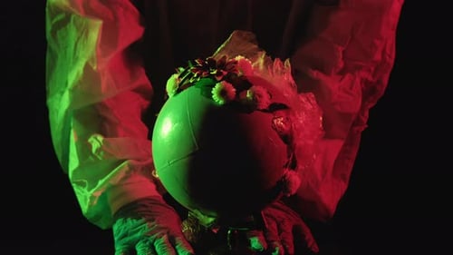Person Holding Globe Covered in Flowers and Plastic