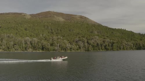 Aerial shot orbiting around a boat with tourists navigating on Lacar Lake in San Martin de los Andes