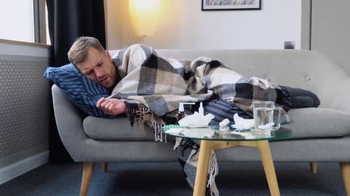 Junger Mann hat ein Fiebermessthermometer und misst die Körpertemperatur