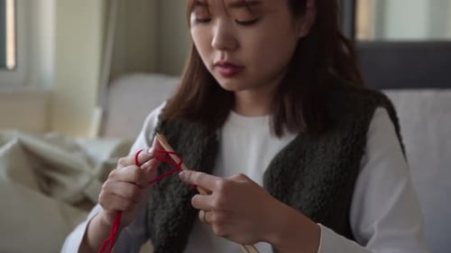 Woman Knitting with Red Yarn at Home