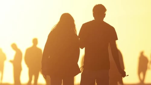 Silhouetted Couple Walking on Beach at Sunset