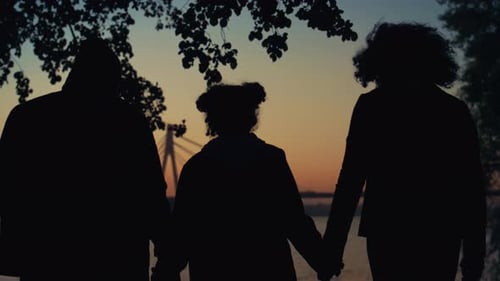 Familiensilhouette, Händchen haltend, beim gemeinsamen Gehen auf der Sunset River Bridge in Nahaufnahme. Unbekannt