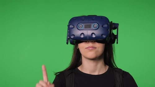 Retrato de una mujer joven con gafas de realidad virtual sobre un fondo verde