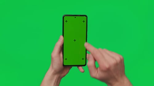 Male Hand Holding a Smartphone with Vertical Green Chroma Key Screen Isolated on Green Mobile Phone