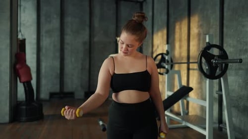 Young Woman Working Out at Gym With Dumbbells