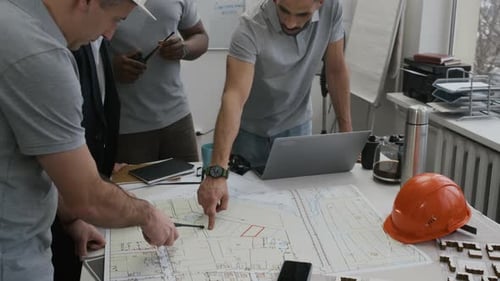 Civil Engineers Standing by Table with Blueprints Analyzing Work in Office